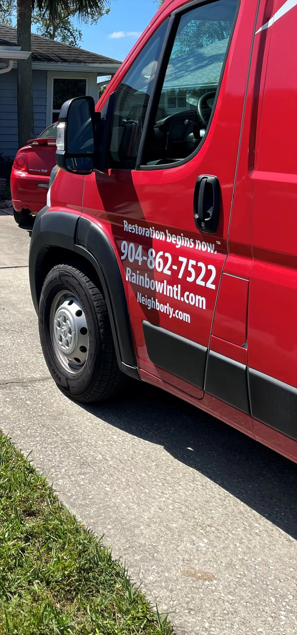 Side door of a red Rainbow service van parked in a driveway